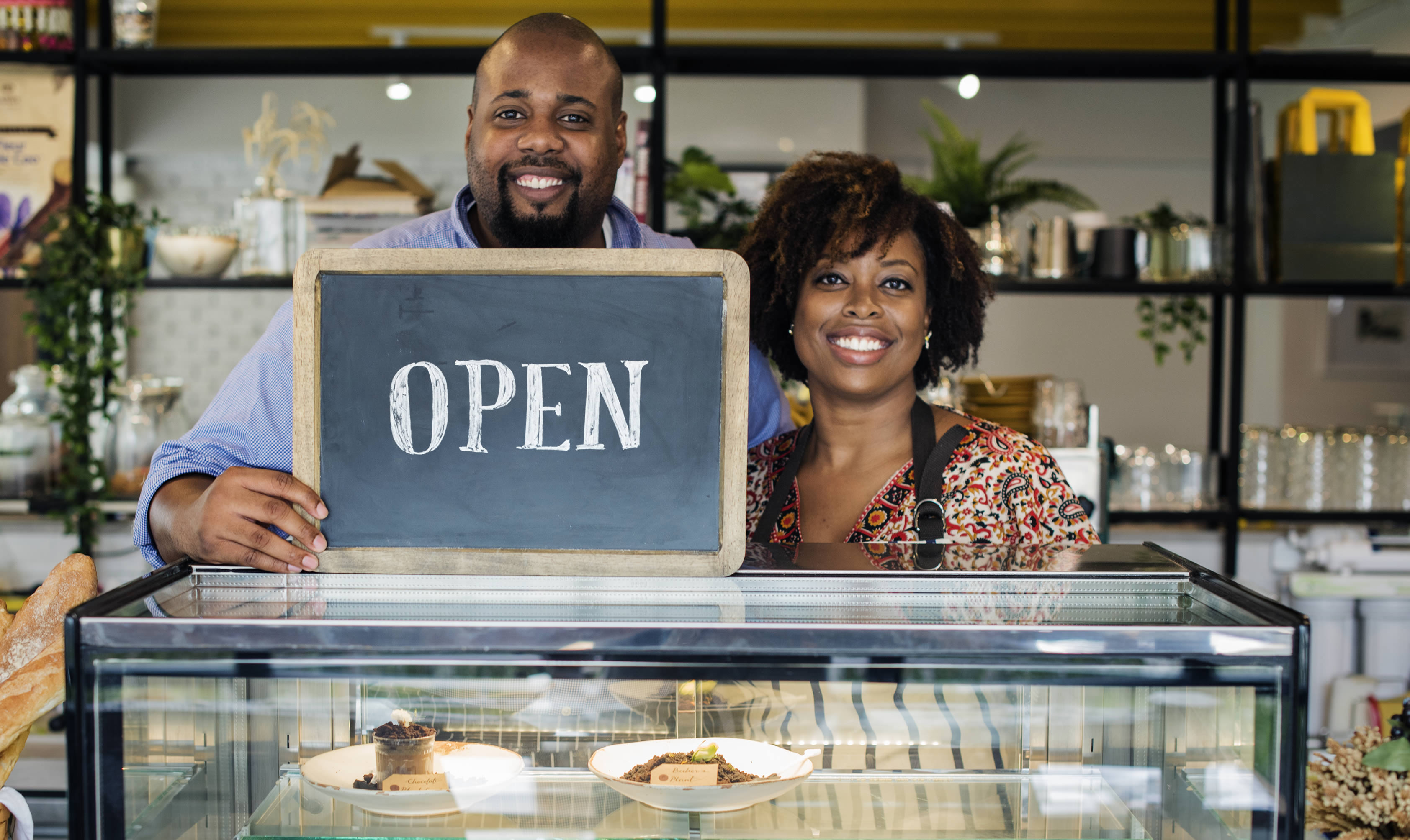 Two small business owners proudly opening their shop